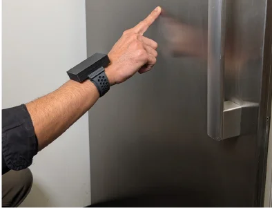 Tapping a refrigerator door: the band senses the moment the finger makes contact, even though the door has no sensors.